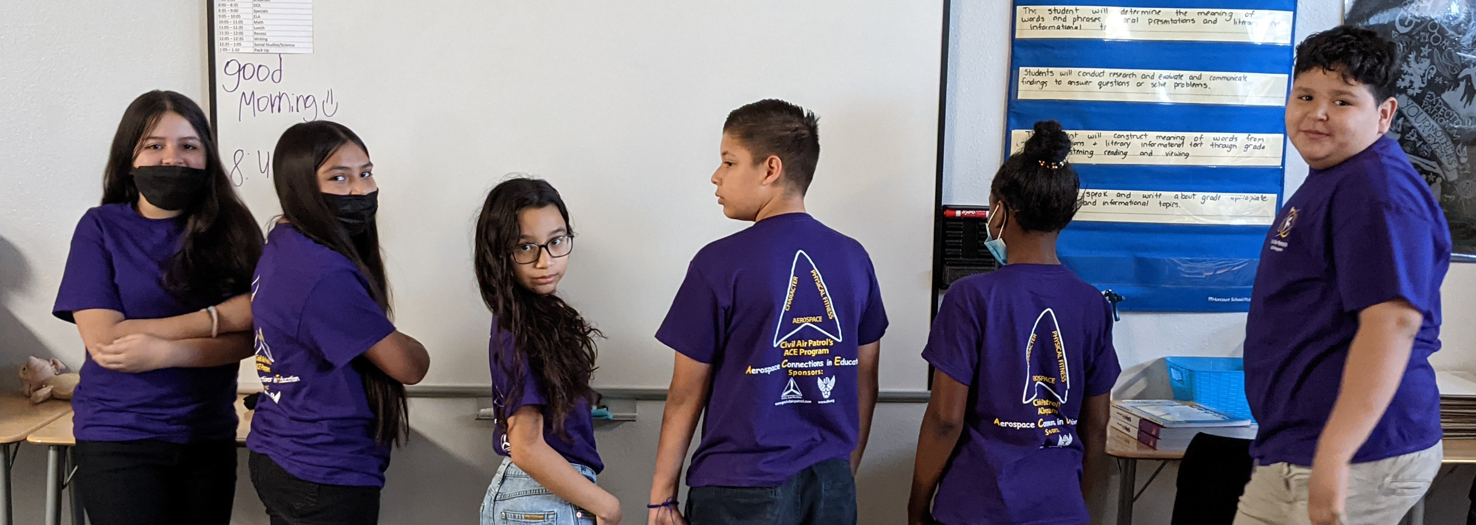 Students pose facing away so that the backs of their purple ACE T-shirts are seen 