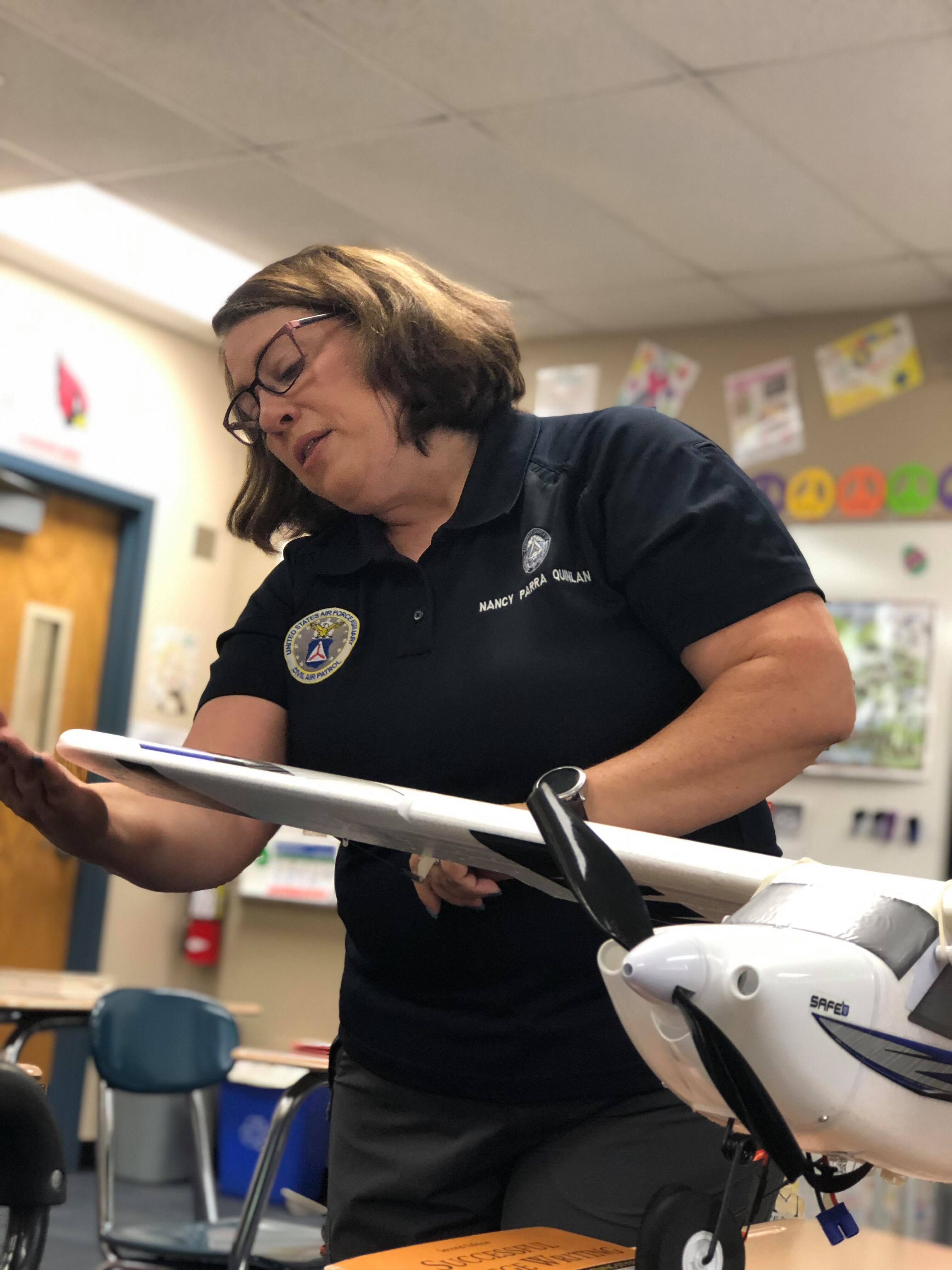 Capt. nancy Parra-Quinlan works in her classroom with an remote control model plane
