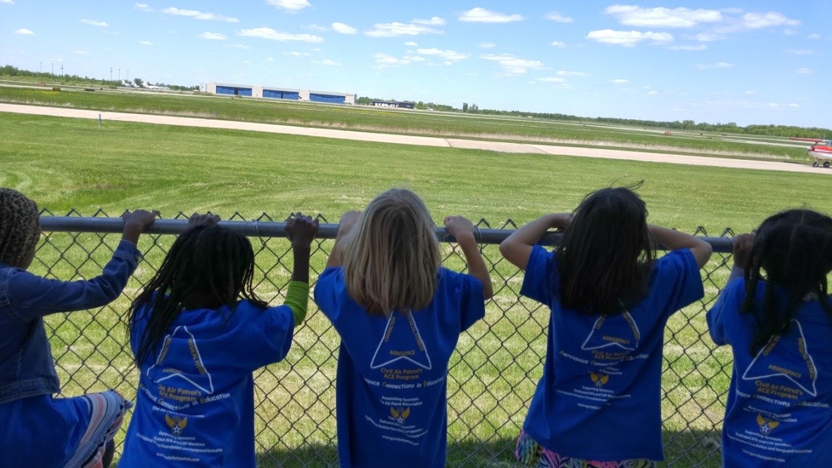 Students watch planes on a runway