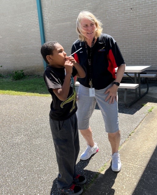 Teacher Mare Gilmore works outside with a student who is launching a straw rocket
